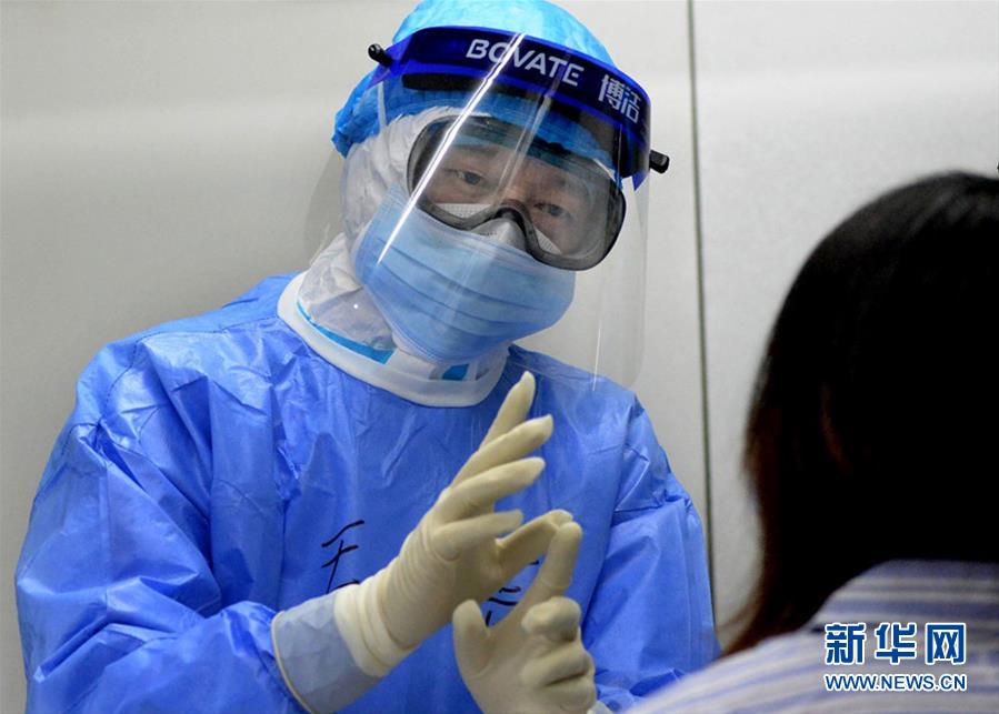 陆军军医大学第一附属医院感染病科主任毛青在武汉火神山医院隔离病房向患者了解病情(2月20日摄)。 新华社发(吴尚哲 摄)